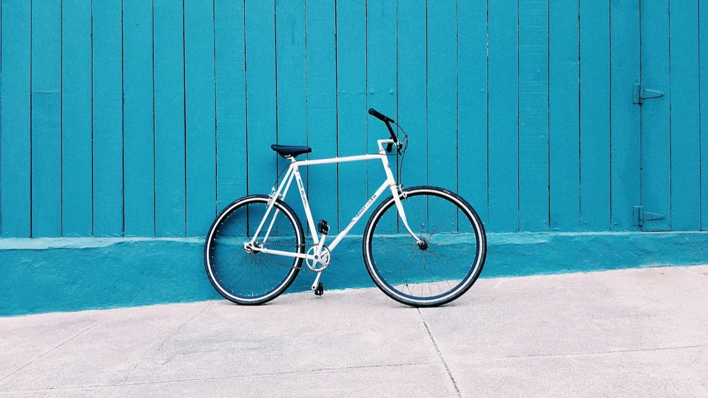 White city bike leaning on a blue wall