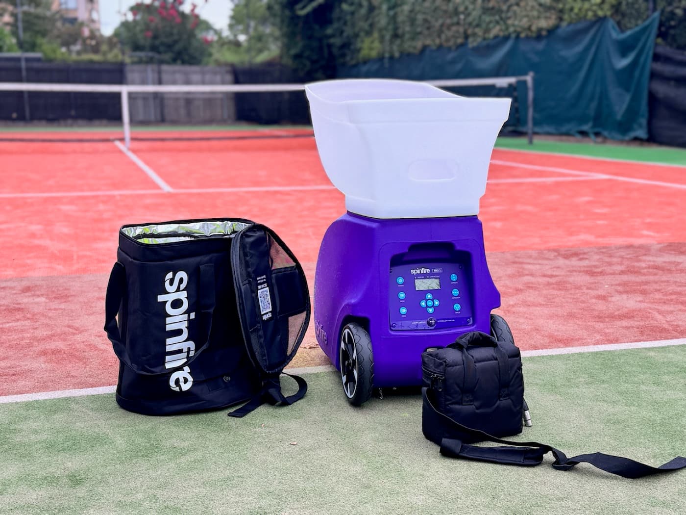 Purple Spinfire ball machine on a tennis court with its ball bag